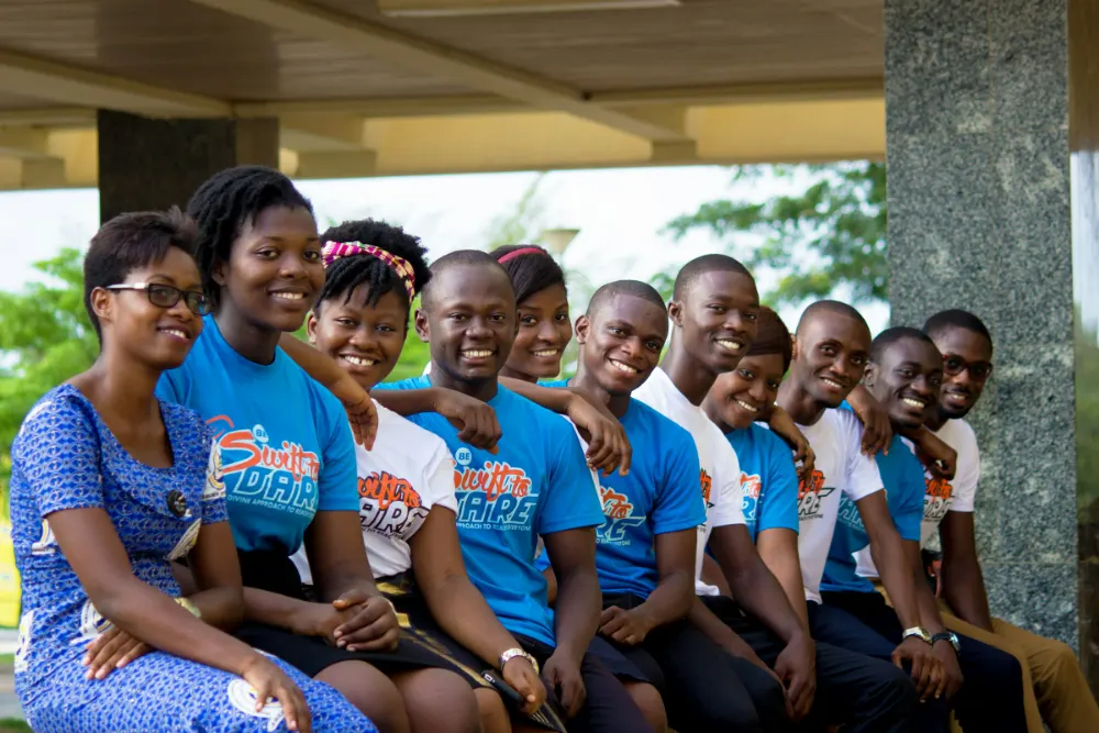 A group of young trainees in matching programme T-shirts sitting together and smiling